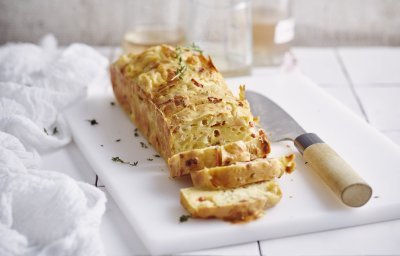 Een cake die niet zoet is, maar hartig. Wij maakte hem met appel, kazen van bij ons en spekjes... heerlijk! Hij ligt aangesneden op een witte snijplank en werd afgewerkt met verse tijmblaadjes. 