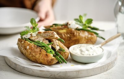 Twee gepofte aardappelen liggen op een plateautje, ze zijn gevuld met 