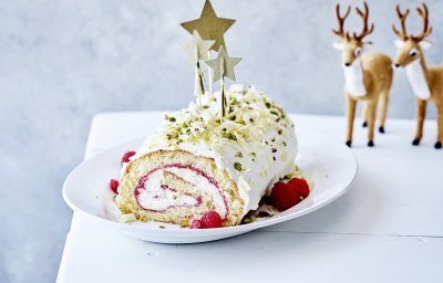 Homemade kerststronk met aardbei en framboos. Als afwerking werden er nog witte chocolade schilfers, gehakte pistachnootje en gouden sterren aan toegevoegd. Er staan twee reetjes achteraan op de tafel als sfeer.