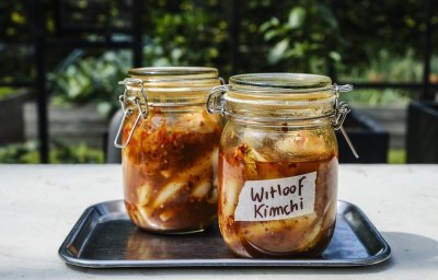Er staan twee weckpotten op een inoxe plateau gevuld met kimchi. Hij is roodkleurig door de toevoeging van chilisaus. 