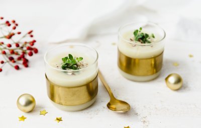 Knolseldersoep in glaasjes met gouden rand, afgewerkt met verse tijmblaadjes en gehakte hazelnootjes. De gouden sterren en kerstballen zorgen voor de feestsfeer in het beeld.