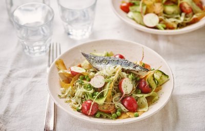 Een kleurrijk bordje gevuld met groenten, noedels en stukje gebakken vis er bovenop. 