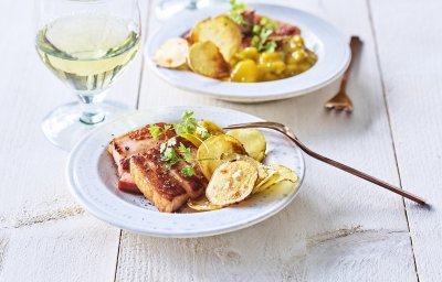 Er staan twee bordjes op tafel gevuld met krokant buikspek, krokante aardappelchips en een schep Belgische pickles. Een voorgerechtje boordevol Belgische topproducten! 