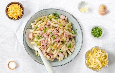 Macaroni met ham, roomkaas en witloof geserveerd in een diep bord. 