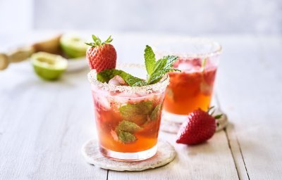 Twee roodgekleurde mojito's op de tafel, afgewerkt met verse munt en nog een aardbei. Alleen al kijken is een feestje, tijd om die cocktail te benuttigen. Het glad kreeg zelfs een suikerrandje. 