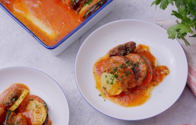 Twee bordjes staan op tafel met een uitgeschepte portie vanuit onze ovenschotel. We maakten een ovenschotel met plakjes groenten en schijfjes gehakt met tomatensaus.