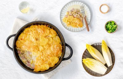 Heerlijke gratin met witloof, hesp, aardappel en veel kaas! De ovenschotel is klaargemaakt in een ronde zwarte ovenschotel, hieruit is al 1 portie uitgeschept. 