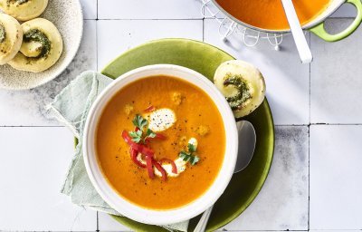 Paprikasoep met pestorolletjes staat op het aanrecht klaar om te serveren. 