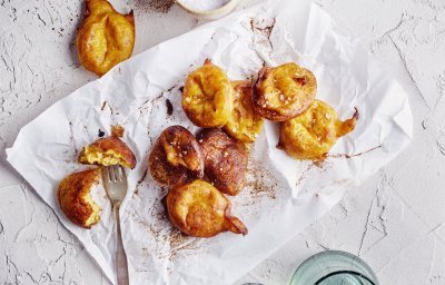 Op het aanrecht liggen enkele pompoenbeignets op een wit boterpapiertje. Ze hebben een mooie oranje gloed, net gouden beignets. Er ligt een vorkje langs meteen te prikken en te eten. 