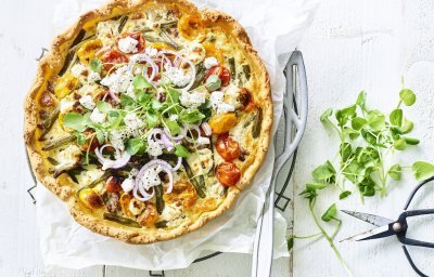 Kleurrijke quiche gevuld met boontjes, kertomaat, geitenkaas en lamsgehakt. Ja, eentje met gehakt. We werken hem af met verse rode ui en waterkers. Ten aanval! 