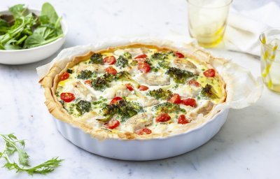 Het lijkt alsof de quiche net uit de oven komt. Ze staat nog ongesneden op het aanrecht klaar om aan te snijden en te smullen van deze hartige taart met broccoli, tomaatjes en schelvis.