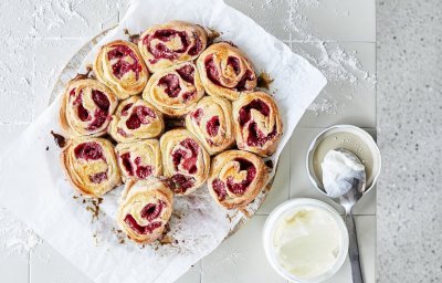 Rolletjes gemaakt van beslag met yoghurt, gevuld met framboosje. De rolletjes liggen tegen elkaar in een cirkelvorm. Heerlijke kleuren om naar te kijken en nog beter om op te eten.