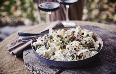 Een witloofsalade met yoghurtdressing, selder, rozijnen, appel en gember. Echt eentje om duimen en vingers van af te likken. De salade is geserveerd in een groot diep bord en staat op een boomstronkschijf.