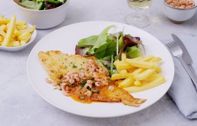 Een bordje gevuld staat op tafel, klaar om te beginnen. Er ligt een gebakken schartong op met een citroensausje afgewerkt met garnaaltjes. Bijgerechtjes zijn een groene salade en verse frietjes.