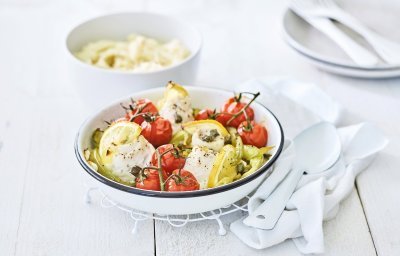 In een ronde ovenschaal liggen de tongrolletjes te blinken. De ovenschotel werd aangevuld met kerstomaatjes in trosvorm en stukjes groene paprika. Er werden ook partjes citroen toegevoegd voor een extra frisse smaak. In de achtergrond is een kommetje gevuld met puree.