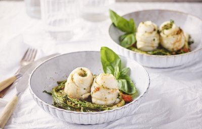 Twee bordjes staan op tafel, het zijn diepe borden in een lichtblauwe/grijze kleur. Ze zijn gevuld met de lente-uitjes en zeekraal op de bodem in een nestjesvorm. Hier bovenop liggen de schartongrolletjes. Het gerechtje is afgewerkt met de tomatenboter en crumble van ansjovis en peterselie.