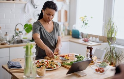 Vrouw maakt een salade van verschillende groenten in haar keuken