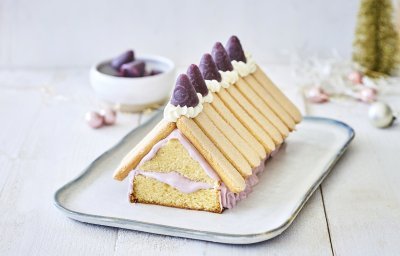 Op een schaaltje staat een taart in de vorm van een kersthuisje gemaakt uit een cake met lange vingers en cuberdons. De cake is de vorm van het huis en hierop werden de lange vingers gelegd als dakplaten. De cuberdons staan in een toefje slagroom hier bovenop. 