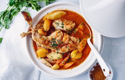 Een witte tajine staat op tafel met deksel open, deze tajine is gevuld met heerlijke producten van bij ons, denk maar aan konijn, aardappel, wortelen, pastinaken en tomaten. Dit in combinatie met smaakmakers uit het Midden-Oosten, een toppertje!