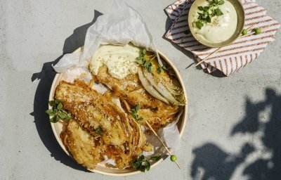 De tempura is knapperig goudgeel. Hij ligt op een wit boterpapiertje in een schaal. De wasabimayo is er langs geplaatst en afgewerkt met enkele sesamzaadjes. 