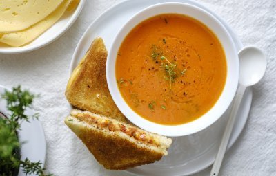 Een heerlijke kom soep staat klaar op tafel in een wit kommetje. Wij serveren hem met een toast van kaas en tomaatjes. Een heerlijke en voedzame lunch.