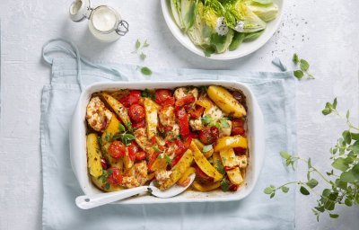 Een heerlijke hoofdmaaltijd in één ovenschaal met stukjes aardappel, tomaten, paprika en kip. Er is ook een knapperige salade van little gem met yoghurtdressing.