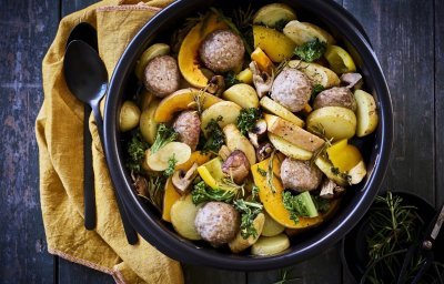 Een heerlijke kleurrijke traybake boordevol herfsttoppers. In een zwarte ronde ovenschotel werd een traybake klaargemaakt met aardappelblokjes, stukjes pompoen, boerenkool en gehaktballetjes. 