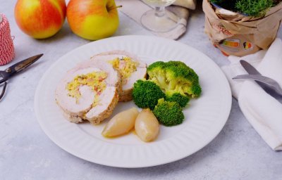 De varkensrollade ligt aangesneden op een bord. Twee ronde schijfjes met in het midden de vulling van appel en spek. We serveren deze varkensrollade met broccoli en de sjalotjes. 