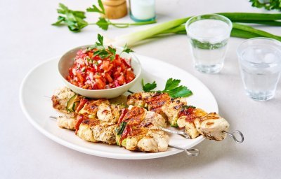 Enkele gegrilde brochettes liggen op een serveerschaal samen met een potje tomatensalsa. De salsa zorgt voor een mooie rode kleur bij de zeeduivelspiesjes.