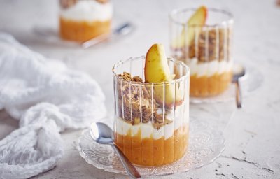 Op tafel staan 3 glaasjes gevuld met dit ontbijtje. Onderaan ligt een lepeltje zoete aardappel, hierbovenop de kwark, granola en een stukje gestoofd appel. De kleuren van dit ontbijtglaasje zijn gewoon om blij van te worden. 