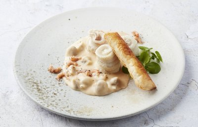 Op tafel staat een portie uitgeschept. Het roomsausje is lichtroze van kleur door de garnaaltjes. 
