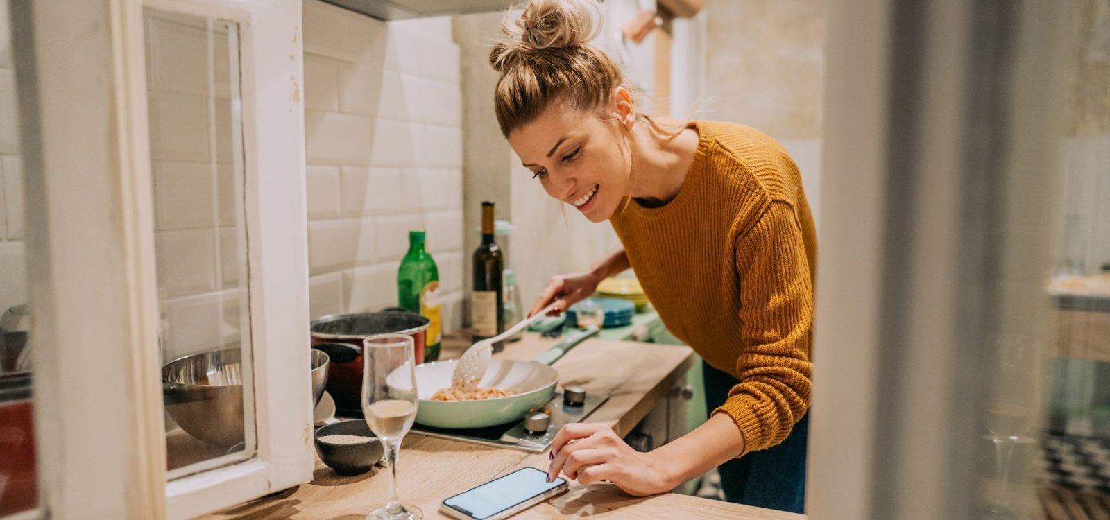 Sfeerbeeld: vrouw aan het koken Vrouw kookt met een Lekker van bij ons recept op haar smartphone