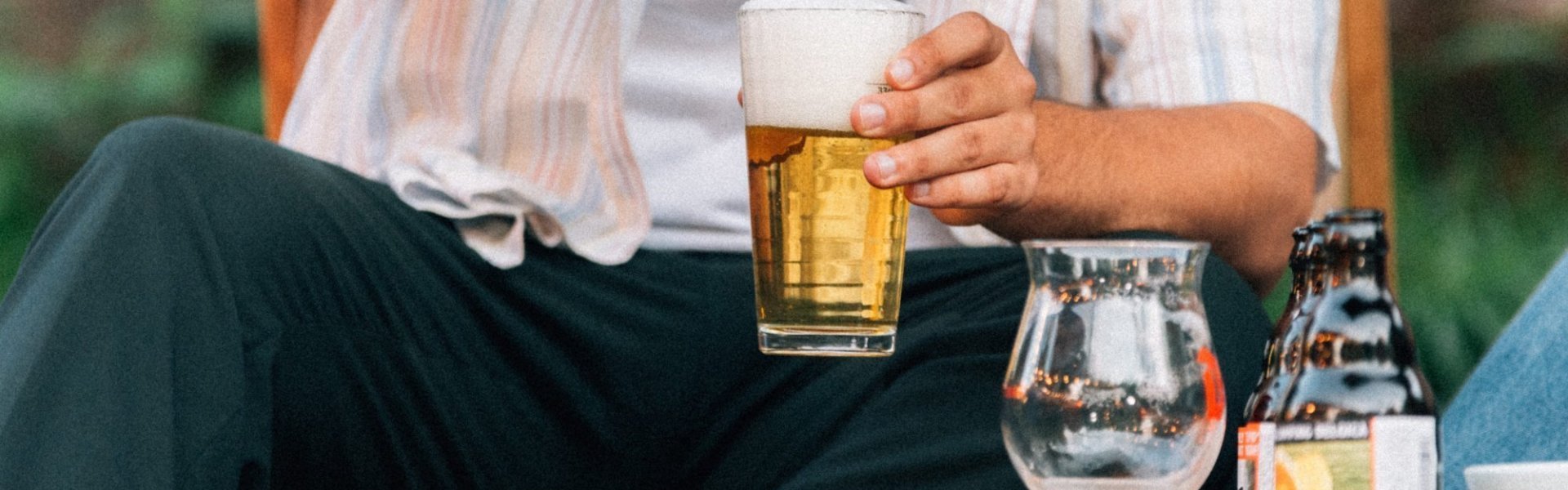 Bier Iemand die geniet van een biertje tijdens een zomers dag. Je ziet de persoon maar helft, dwz zijn middel terwijl hij neerzit in een campingstoeltje.