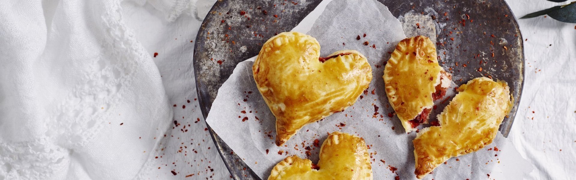 Empanadas gemaakt in hartjesvorm liggen op een bordje te schitteren. Met dit hapje scoor je sowieso bij je geliefde. 