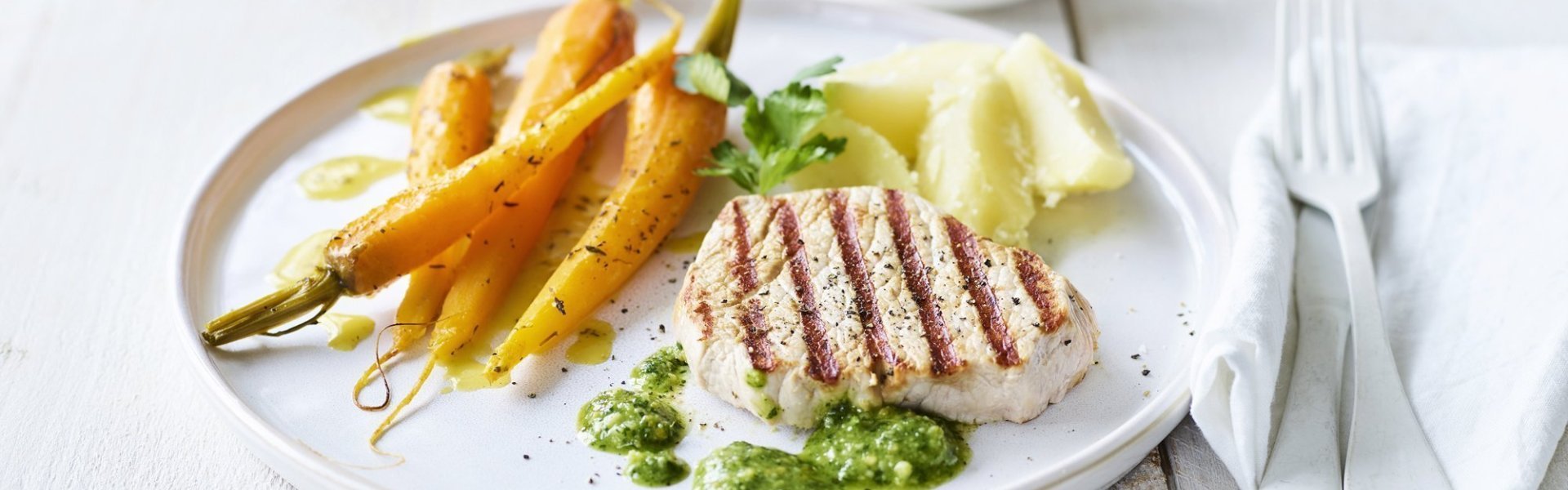 Gegrilde mignonnette met pesto van peterselie en Oud Brugge kaas Een mooi in streepjes gegegrild stukje varkensvlees ligt op een wit bord, geserveerd met gegaarde wortels en gekookte aardappelen. We serveren geen saus bij dit stukje vlees, maar homemade pesto van peterselie en Brugge kaas.