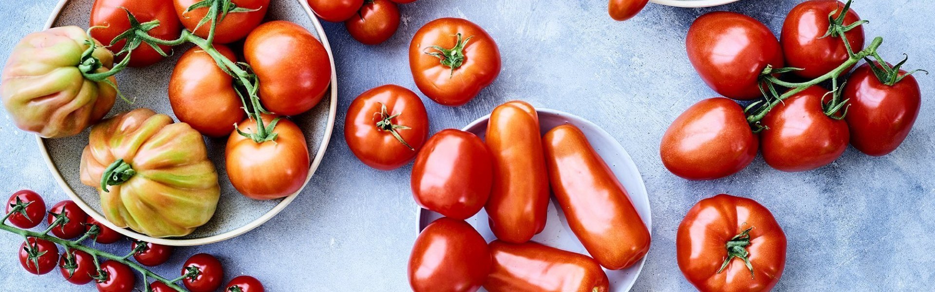 Op het keukenaanrecht, in betonlook, liggen verschillende variëteiten van tomaten. 50 tinten rood in 1 beeld. 