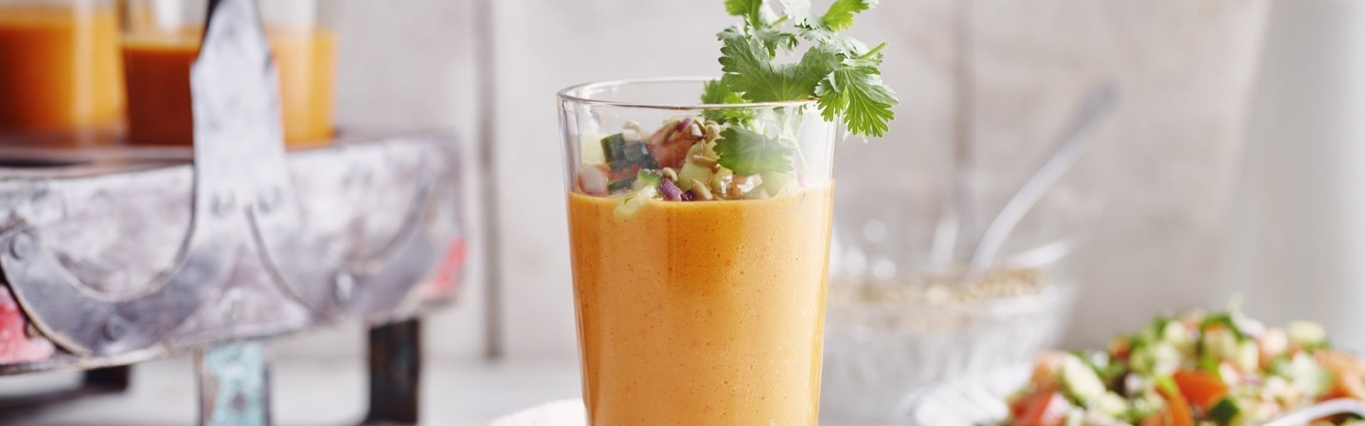 Koude paprikasoep met salsa van komkommer en tomaat Een gazpacho van paprika geserveerd in een groot glas zorgt intens voor een feestlook. Deze koude soep werd gepimpt met stukjes komkommer en tomaat, als afwerking nog enkele blaadjes koriander en zonnebloempitten bovenop.