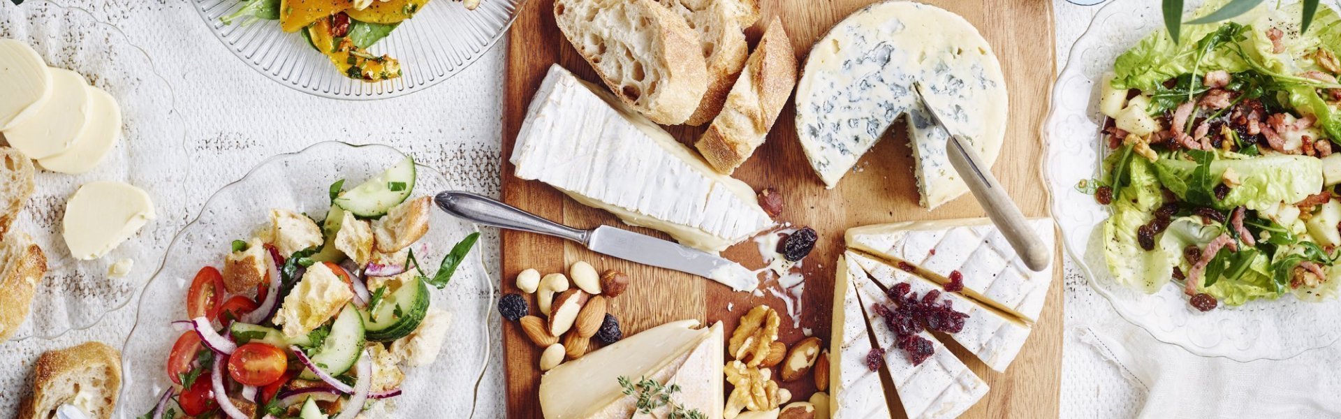 Originele kaasschotel met warm geitenkaasje en partjes peer De tafel staat klaar om aan te vallen. Er staat een kaasplank op met Belgische kazen en verschillende bijgerechten met fruit en groenten. Wijn en brood mogen natuurlijk niet ontbreken bij deze pittige kazen.