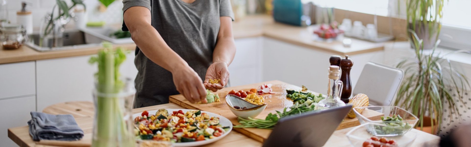 Vrouw maakt een salade van verschillende groenten in haar keuken