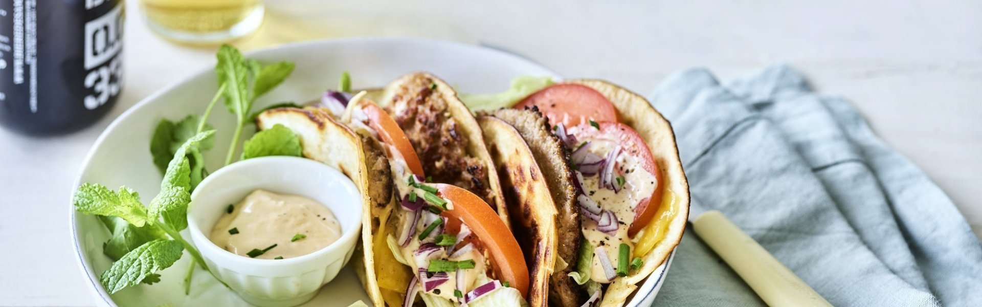 Tacos met hamburger Een twee gevouwen tortilla met hamburger en kaas, die wil ik wel proberen. We werkten hem af met plakjes tomaat, blaadjes ijsbergsla en een homemade sausje. We serveren hem met een fris pintje en nog wat extra sla.