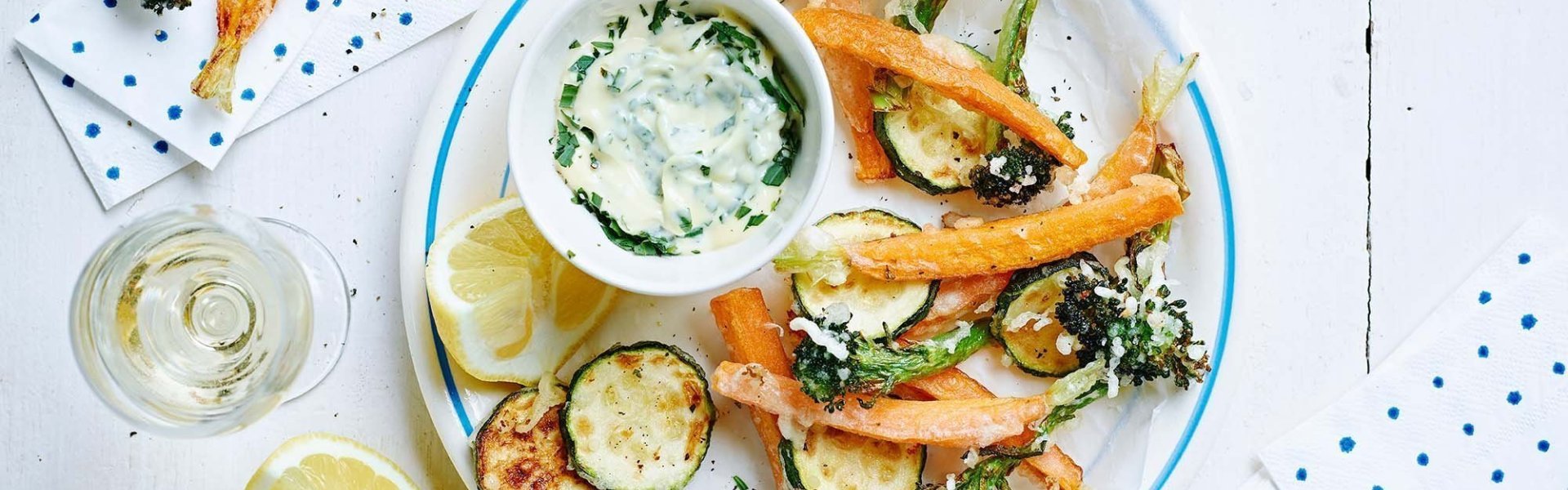 Tempura van groenten Zelfgemaakte tempuragroentjes van wortel, courgette, broccoli en groene boontjes. Ze liggen gepresenteerd op een groot bord met een huisgemaakte kruidenmayonaise als dip. We serveren er wat partjes citroen bij voor de zure toetst wie dit wenst.