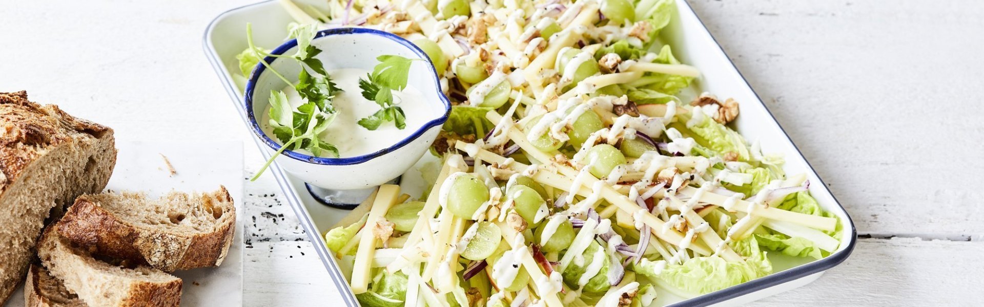 Een heerlijke Waldorfsalade van selder en groen appel. De frisse zurige vinaigrette zit in een apart potje en het brood in dikke sneden ligt er langs. 