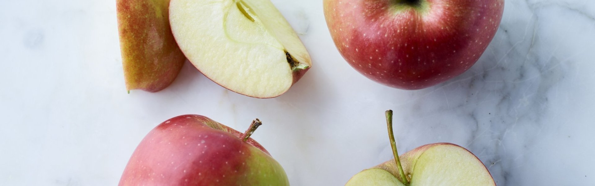 Jonagold appels liggen op marmere keukenblad. Enkele appels zijn aangesneden. 