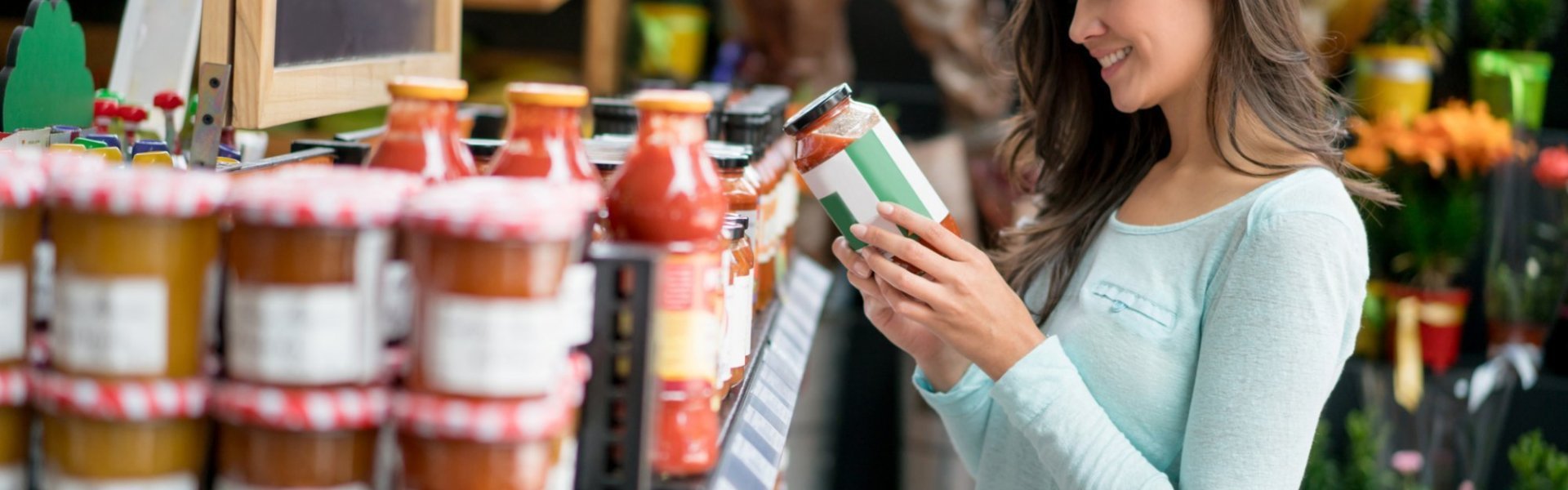 Vrouw kijkt naar biosaus Vrouw kijkt naar bioproduct in biowinkel.